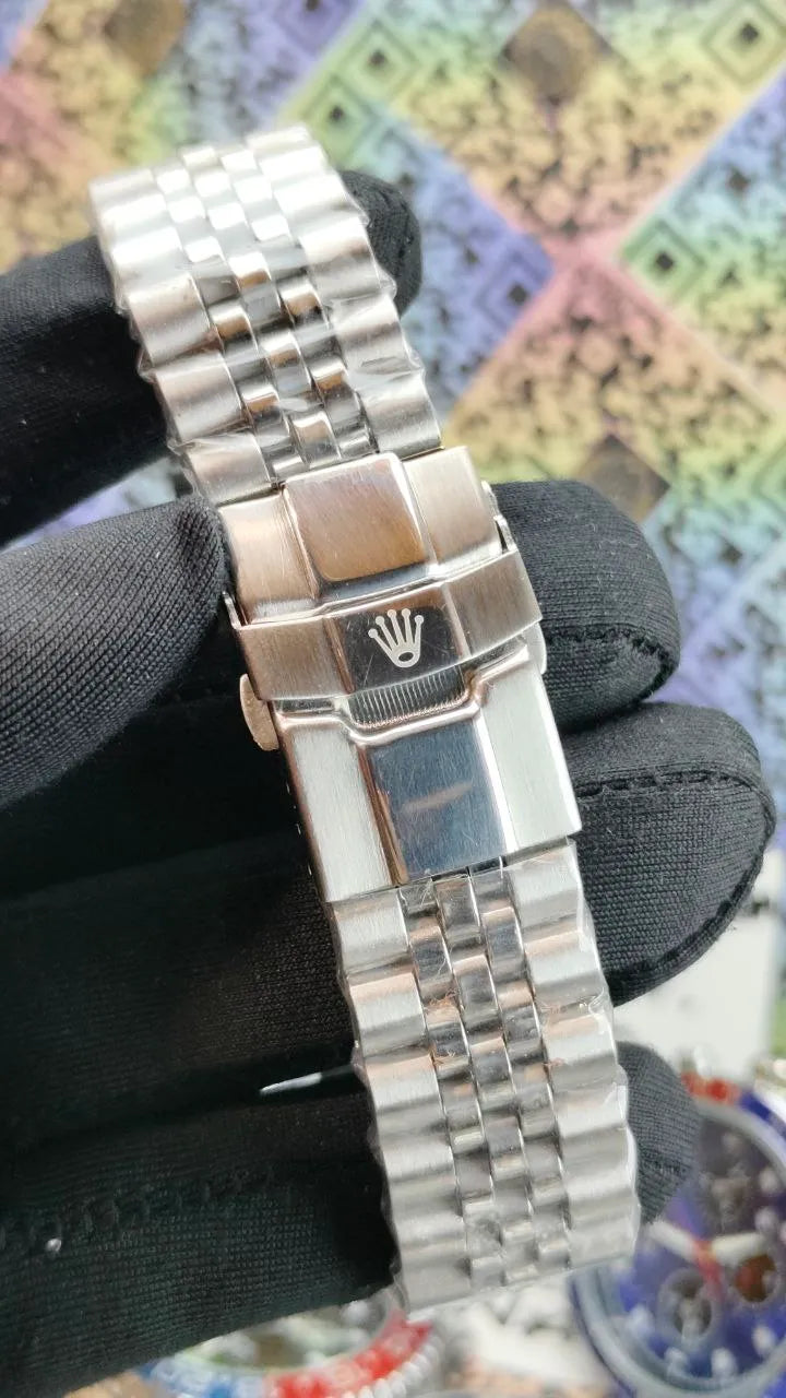 Silver watch with a brand logo held by black gloves against a colorful abstract background