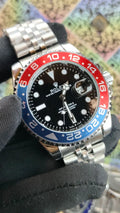 Rolex watch with a distinctive black, red, and blue bezel on a textured surface.