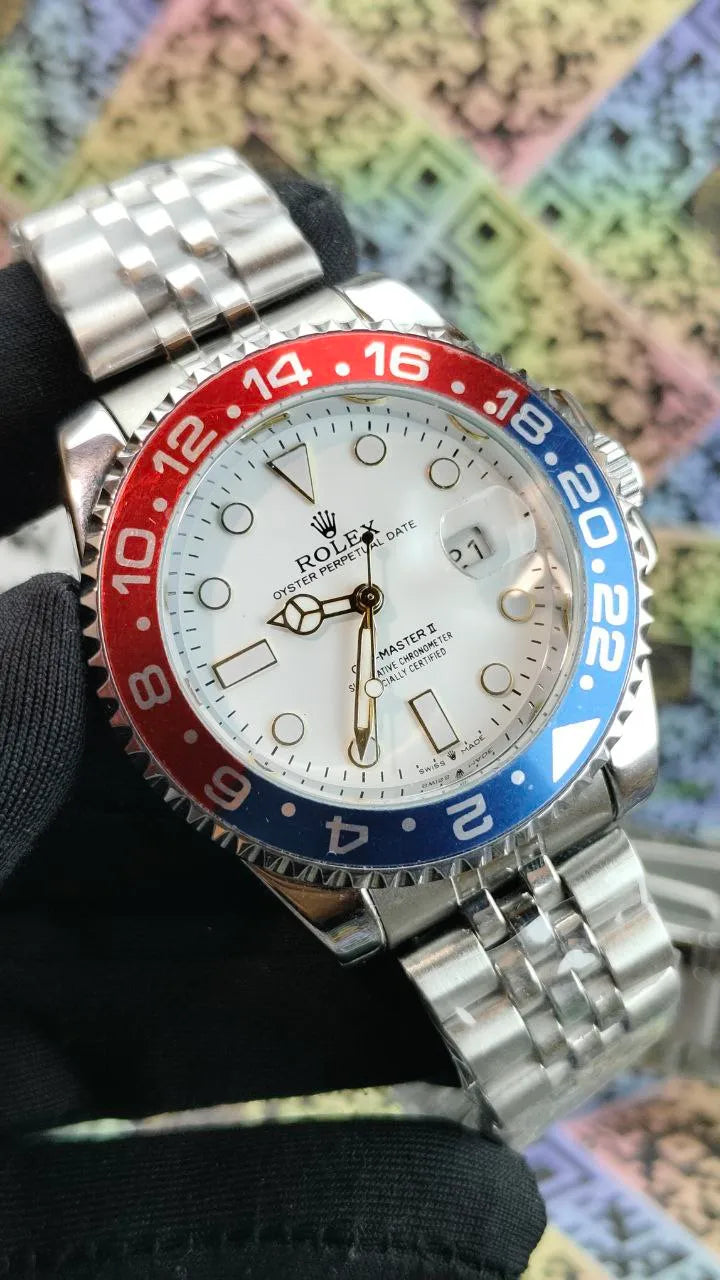 Watch with a silver case, red and blue bezel, and white face held against a colorful abstract background.