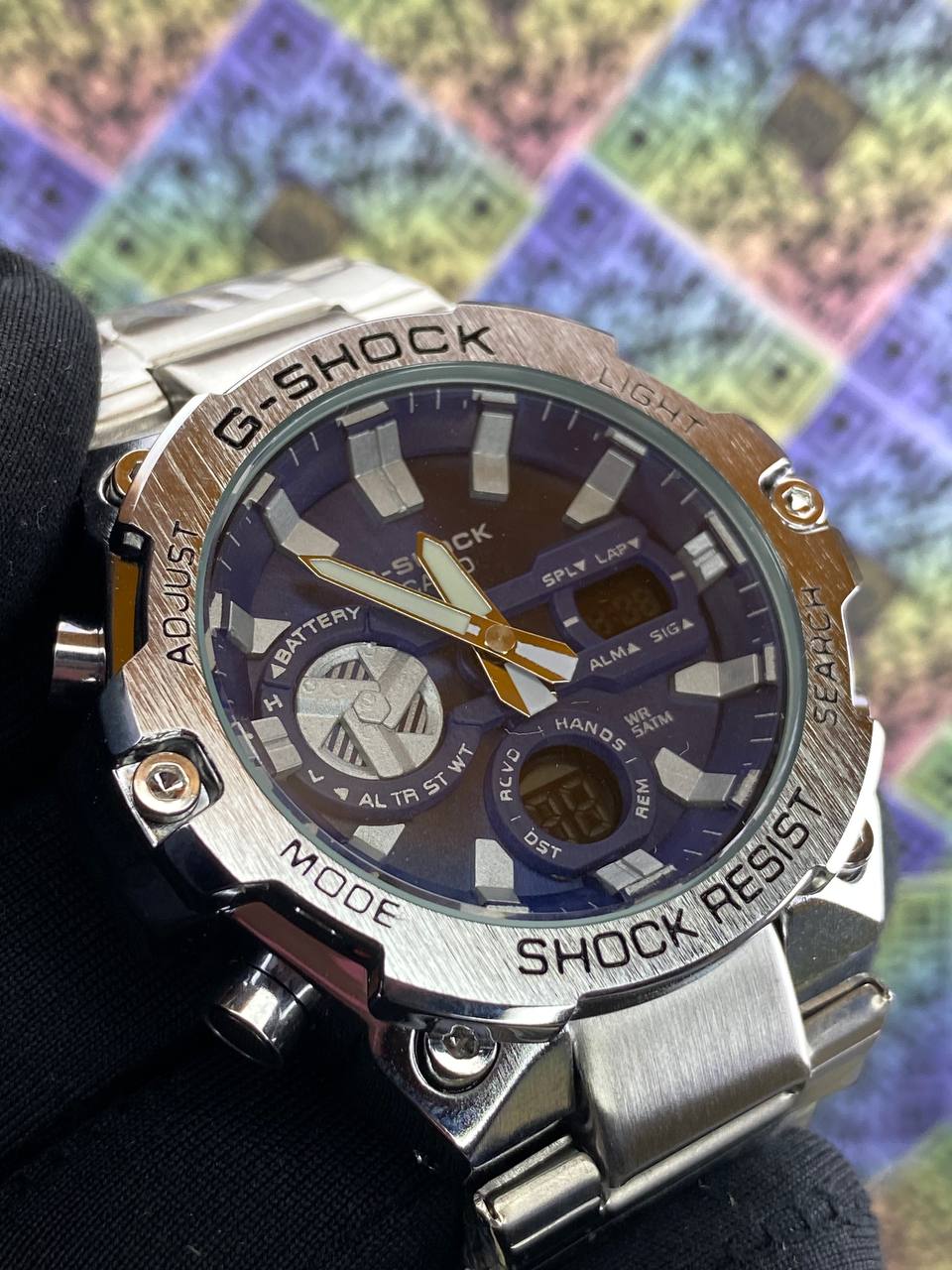 G-Shock watch with a metallic band on a colorful checkered background