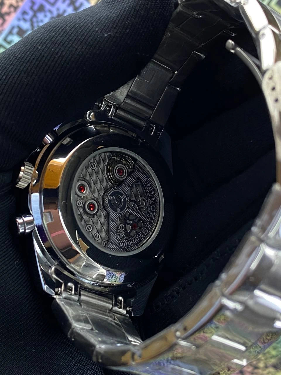Close-up of a mechanical watch with a black strap and silver case.