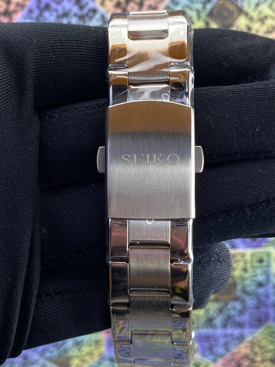 Silver Seiko watch band on a black fabric background