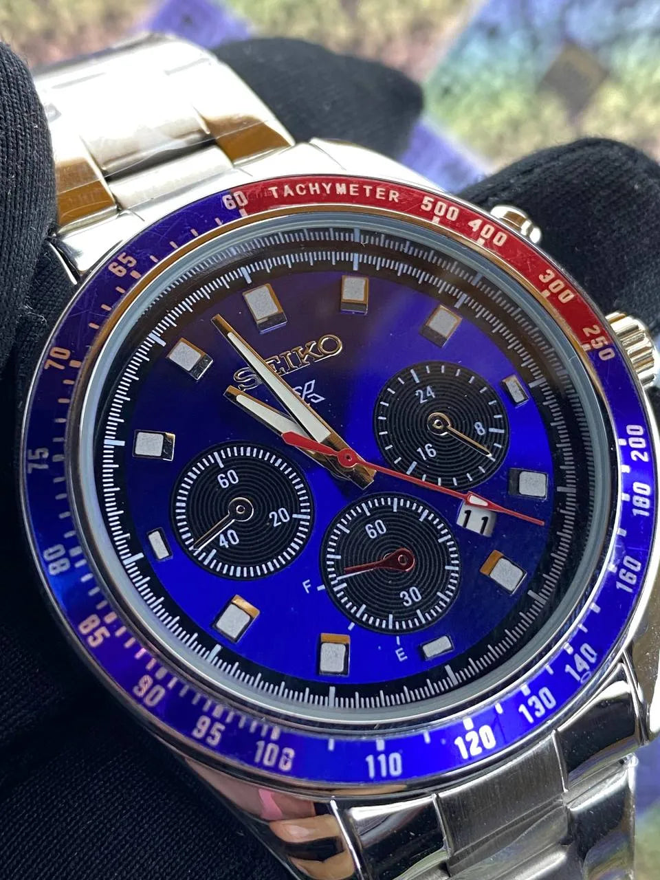 Wristwatch with a blue face and silver case on a dark background